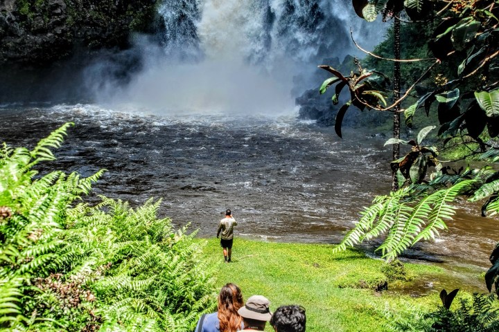 a group of people standing next to a waterfall